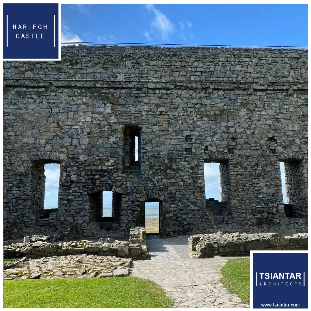 Stone facade of Harlech Castle with multiple arched windows under a clear sky in North Wales, a stone path leading up to it, and the logo of Tsiantari Architects in the corner.