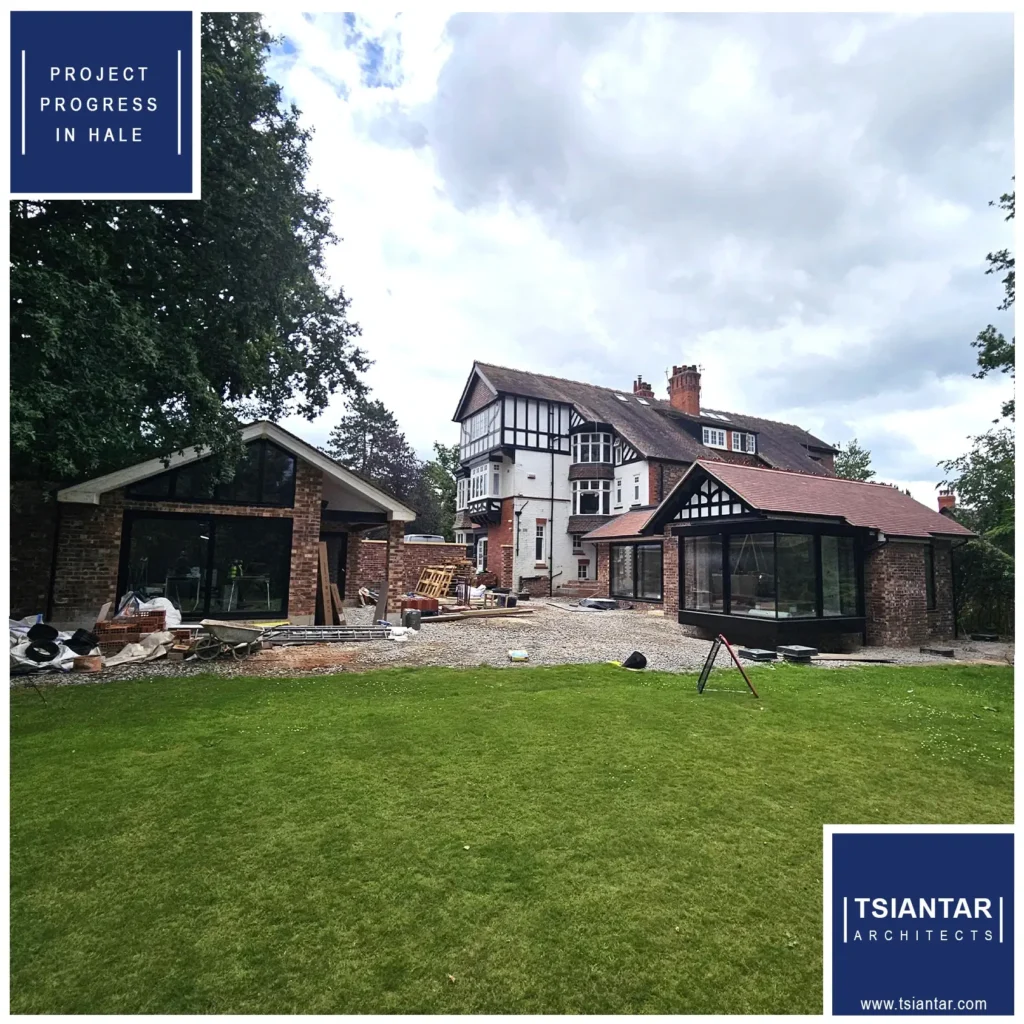 A large house with modern extensions in progress, surrounded by a lawn under an overcast sky. Signs read "PROJECT PROGRESS IN HALE" and "TSIANTAR ARCHITECTS," showcasing the project's status on their website.