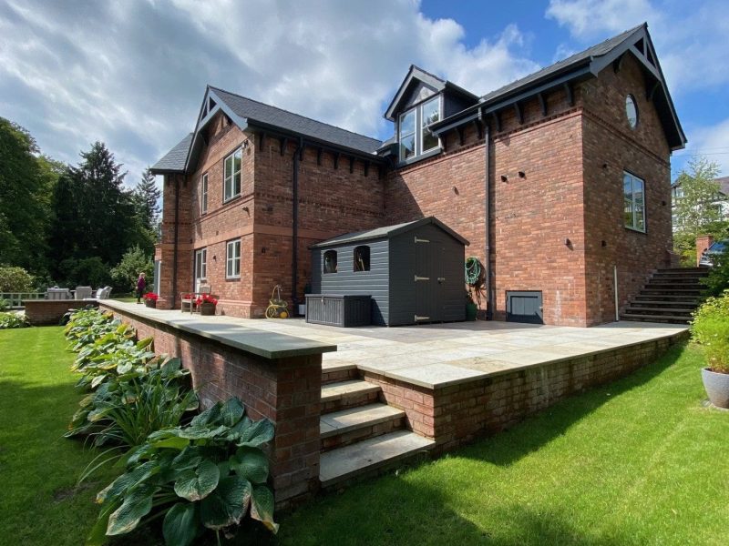 A large brick house in the middle of a lush green lawn.