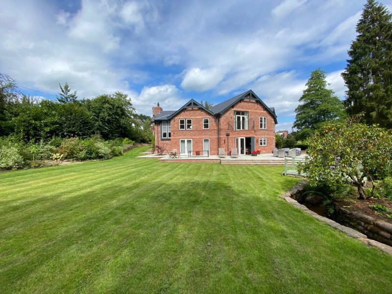 A large red brick house in the middle of a lush green lawn.