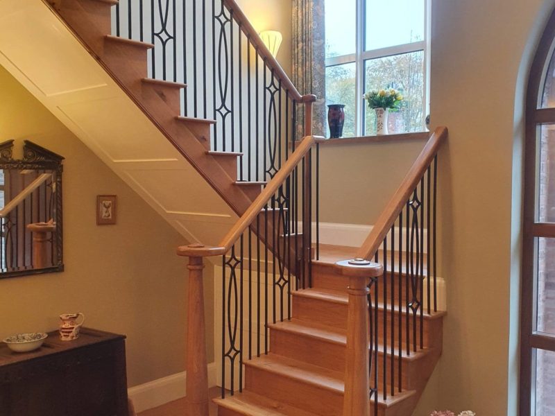 a stair case with a vase of flowers on the floor.