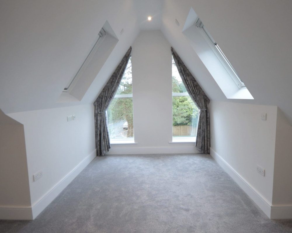 an empty room with two windows and a carpeted floor.