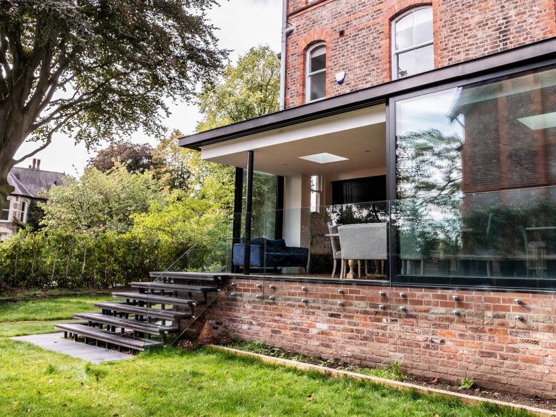 a brick house with glass windows and steps leading up to the front door.