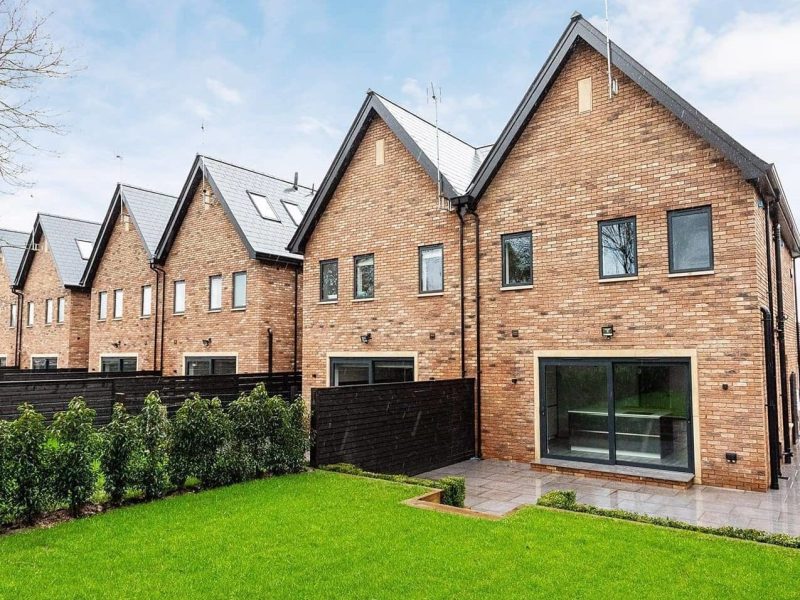 a row of brick houses sitting on top of a lush green field.