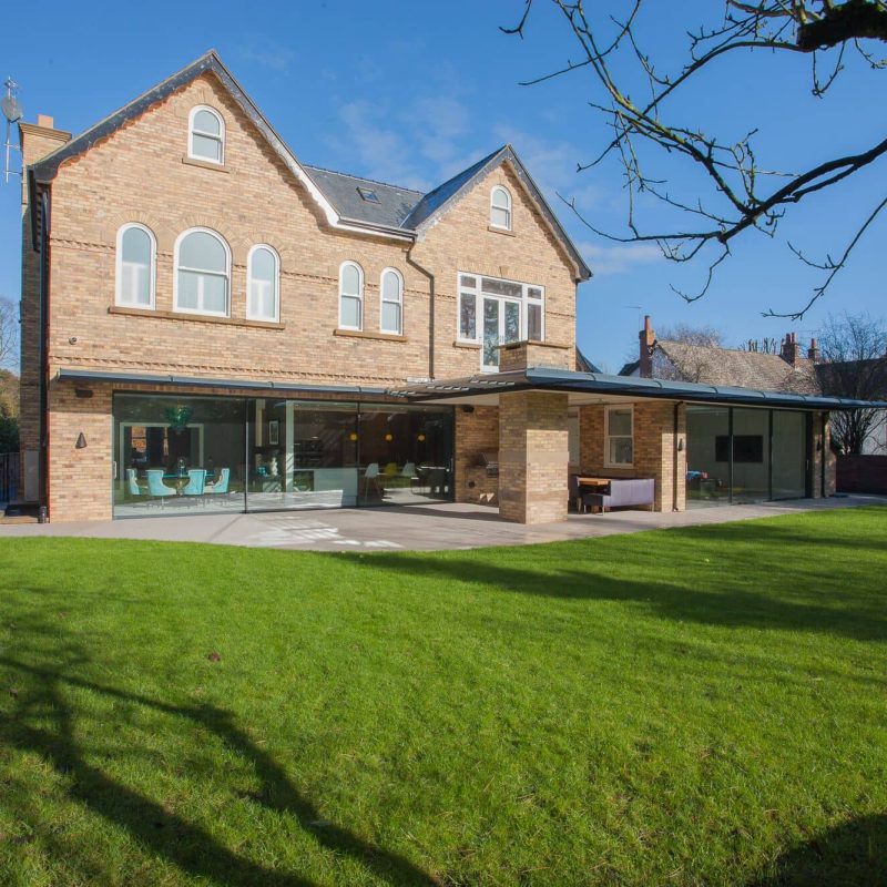 A modern house with a large lawn and trees.